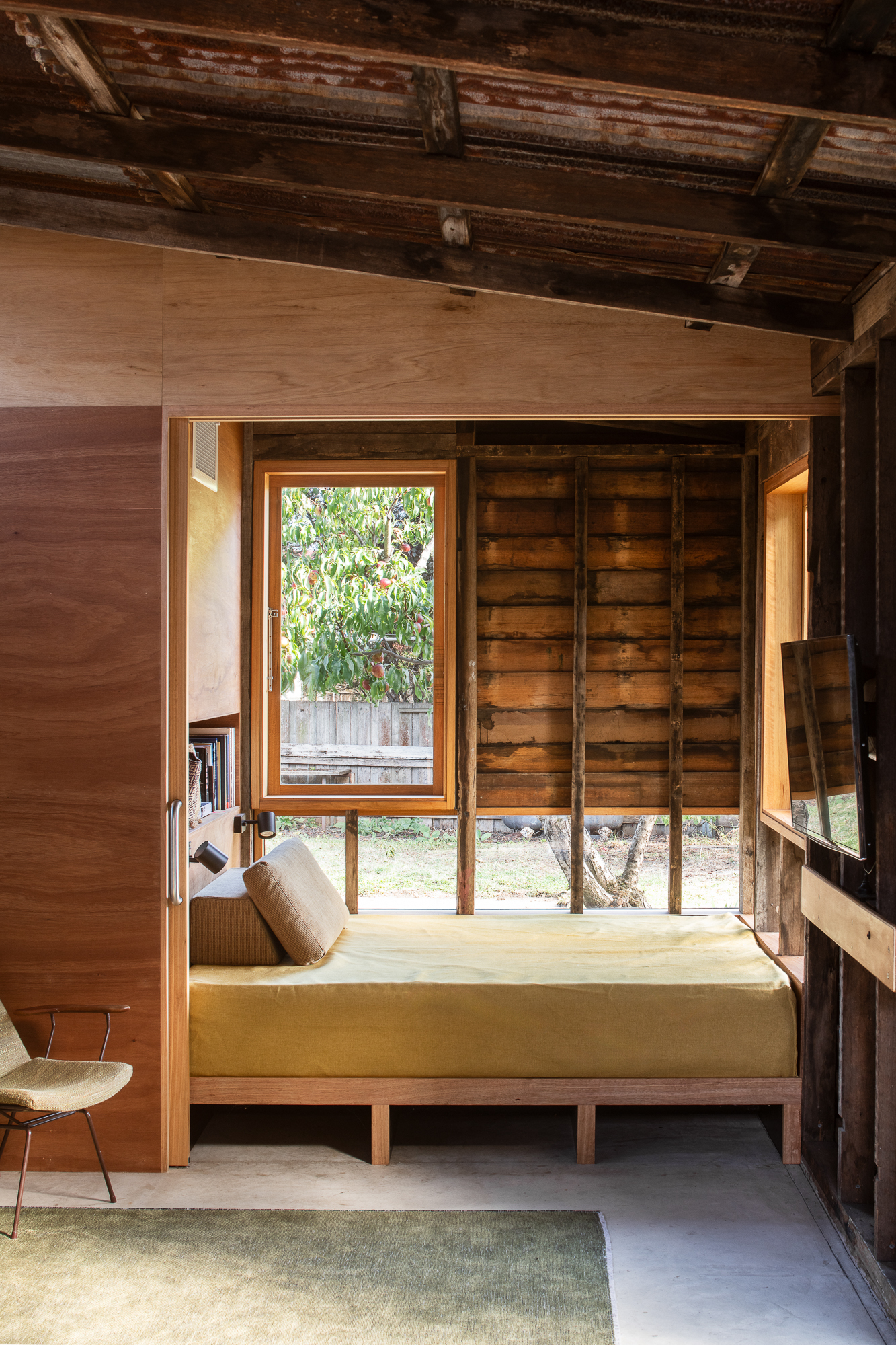 Daybed in alcove with wrap around low window and timber walls.