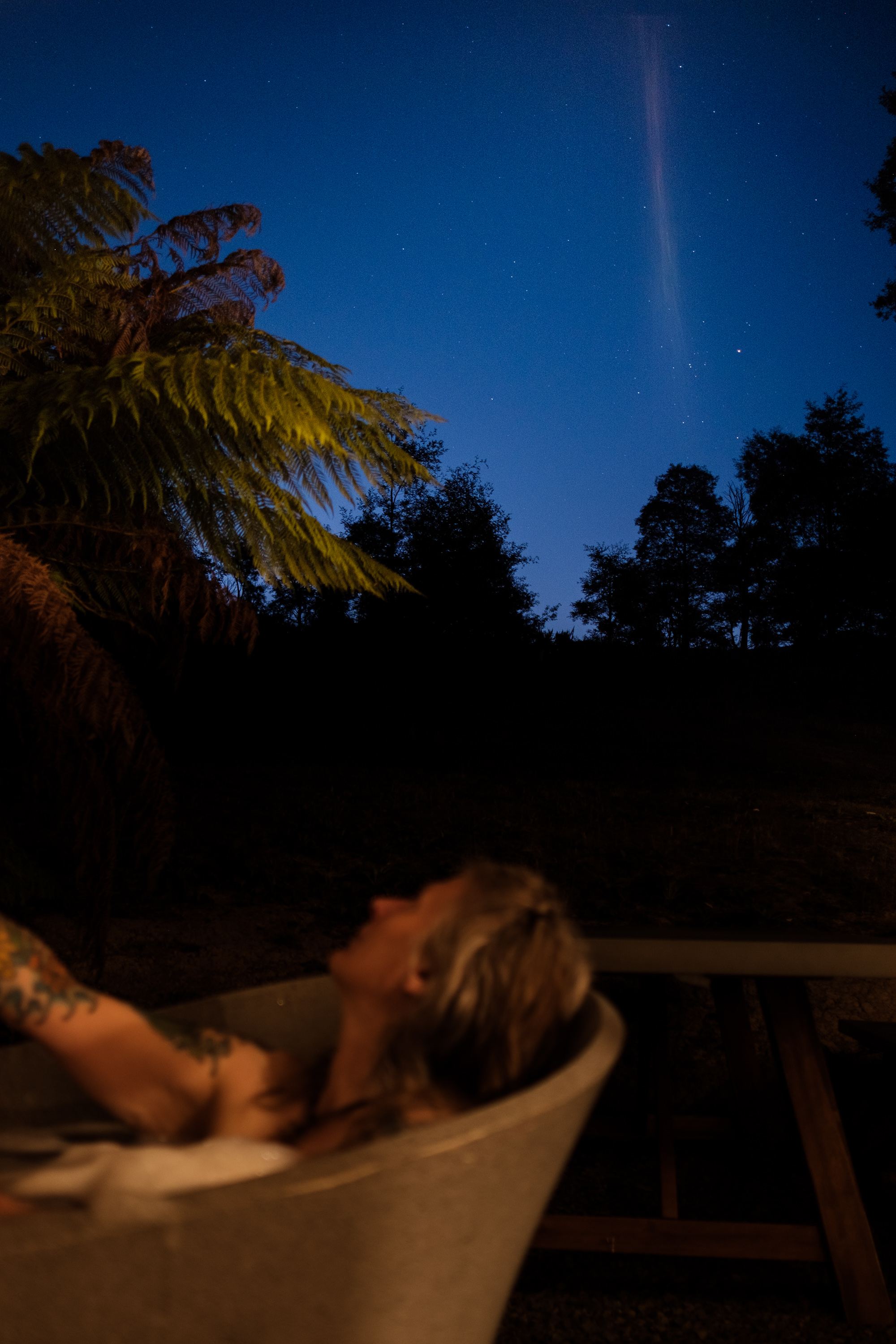 Person lying in the outdoor bath gazing at a starry sky.