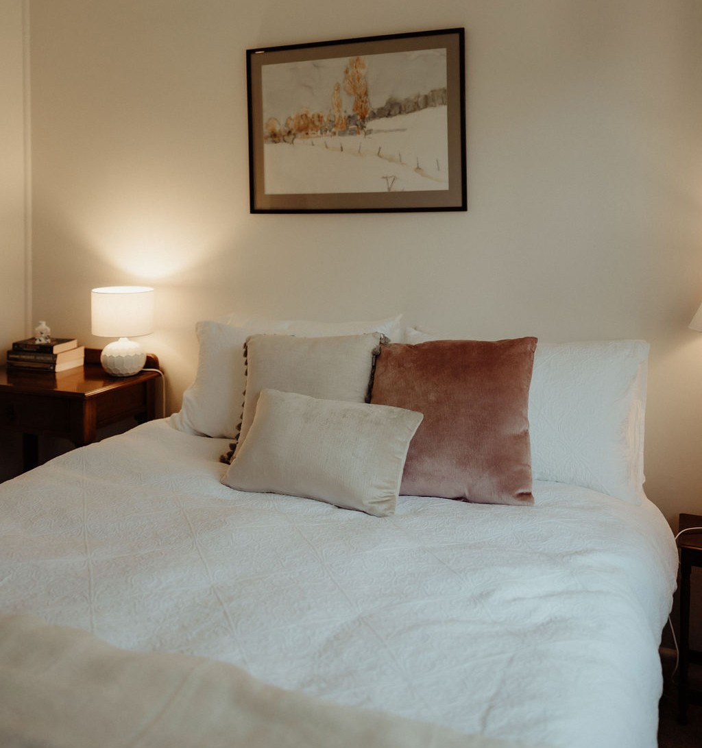 Bedroom three with a queen sized bed in neutral tones, a sunlight north facing room that is calm and inviting.