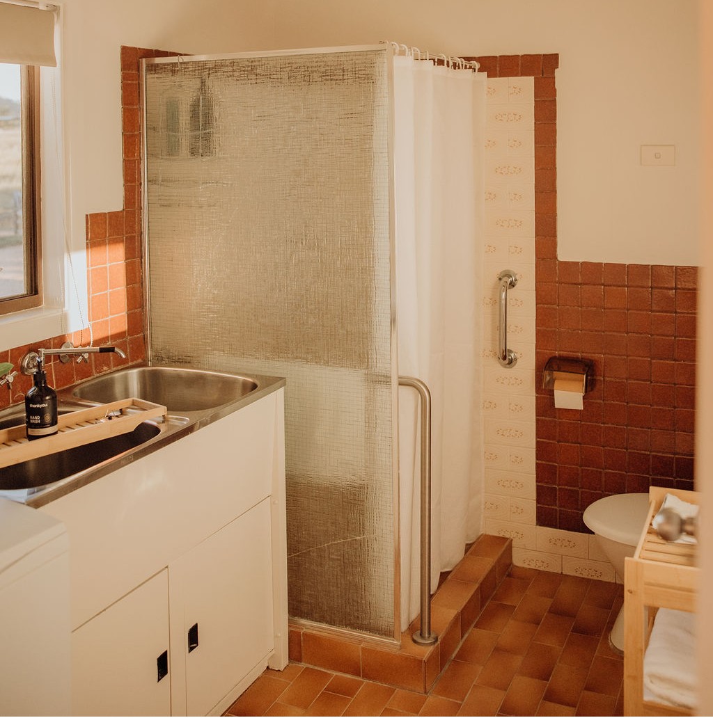 A bathroom come laundry with one step into the shower and handrails for added accessibility.